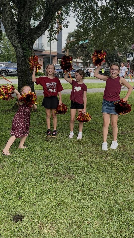 Kids with garnet and gold pom-poms on the grass